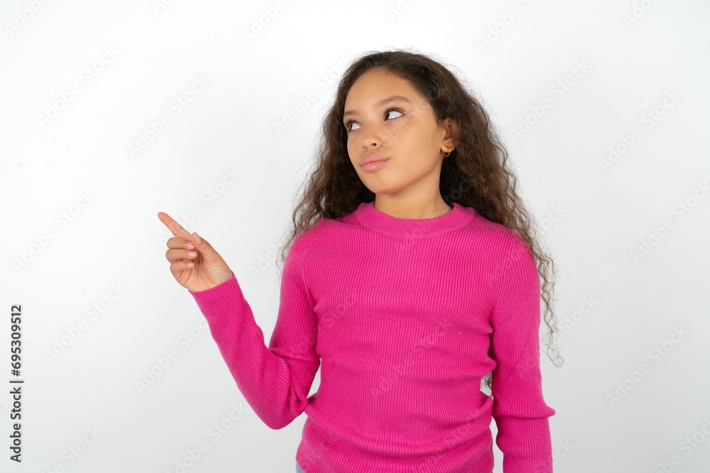 Young beautiful teen girl points at copy space and advertises something, advices best price.