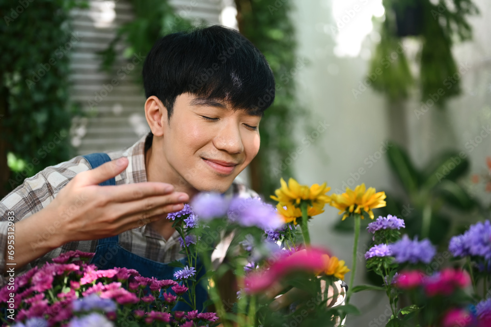 Happy young Asian man smelling flowers in his flower shop. Business, sale and floristry concept. Happy young Asian man smelling flowers in his flower shop. Business, sale and floristry concept.