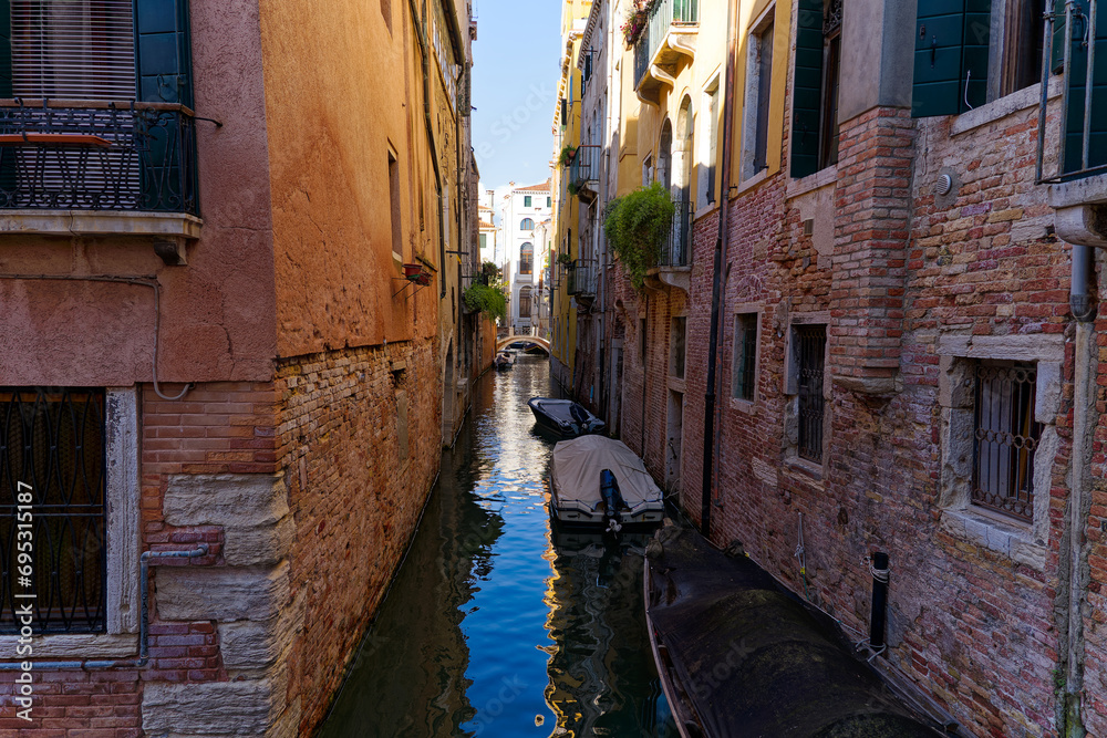 Scenic view of canal with bridge in the background and historic houses at the old town of Venice on a sunny summer day. Photo taken August 7th, 2023, Venice, Italy.