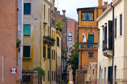 Looking up weathered facade at alley at the old town of City of Venice on a blue cloudy summer afternoon. Photo taken August 6th  2023  Venice  Italy.