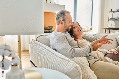 happy couple talking on comfortable couch in modern living room at home, child-free lifestyle