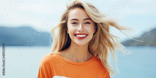 A young, elegant woman with red lipstick enjoys the mountain lake, radiating beauty and happiness. photo