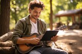 Man playing guitar with digital tablet learning to play in online course sitting on sofa at home