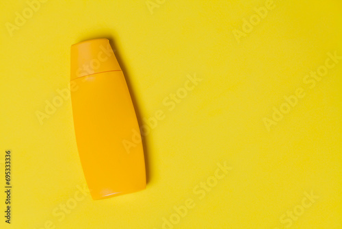 Yellow sunscreen bottle on colored background. Sunscreen concept. Skin care concept. Space for text. Mockup. photo
