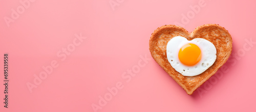 heart shaped fried egg with toast as breakfast for valentine's day. top view. isolated on pink background. banner