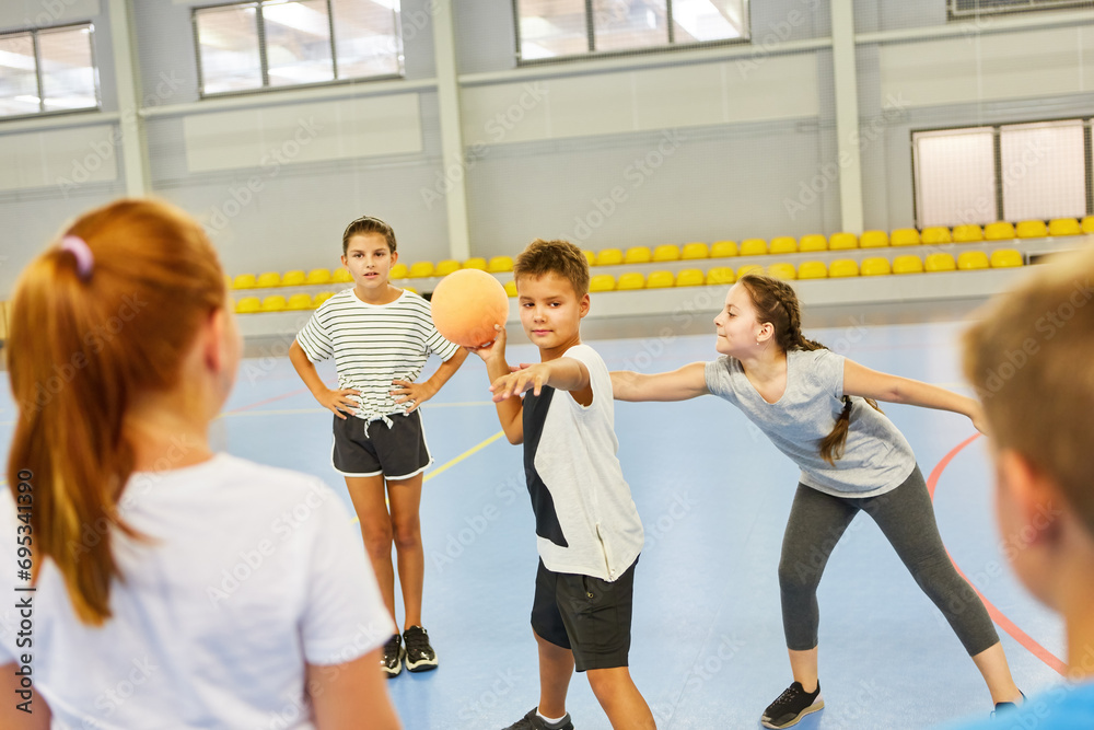 Schoolkids playing with ball during gym class