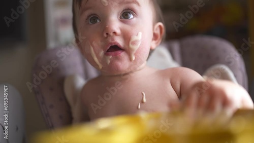 baby eats dirty. happy family lifestyle a kid toddler concept. baby girl dirty sitting messing with food at the table for feeding in the kitchen. grimy toddler in the kitchen photo