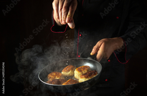 Fototapeta Naklejka Na Ścianę i Meble -  Frying delicious oladyi for breakfast. The cook salts the pancakes in a frying pan. Black space for menu or recipe