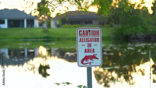 Warning sign about alligator in water in Florida park. Caution and safety during walking near waterfront