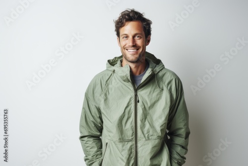 Portrait of a grinning man in his 30s wearing a lightweight packable anorak against a modern minimalist interior. AI Generation