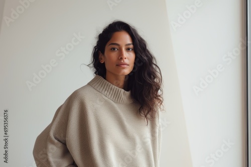 Portrait of a glad indian woman in her 20s wearing a cozy sweater against a modern minimalist interior. AI Generation