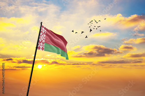 Waving flag of Belarus against the background of a sunset or sunrise. Belarus flag for Independence Day. The symbol of the state on wavy fabric.