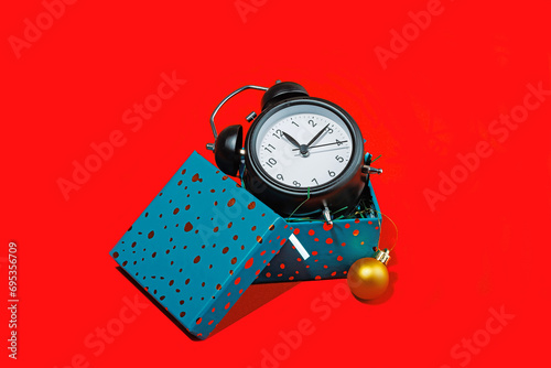 Alarm clock with headphones and gift box on red photo