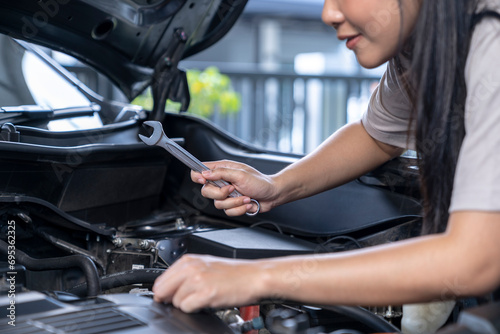 A young woman is repairing a car by herself at home