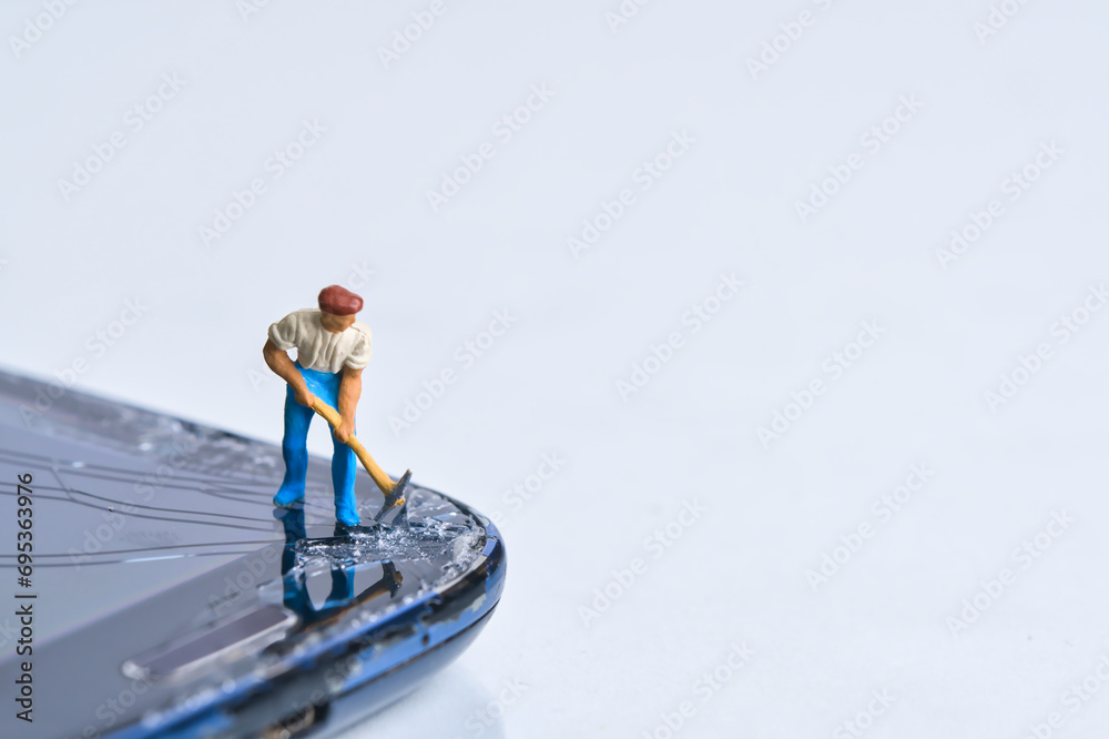 Miniature person with pickaxe damages the smartphone display, white background, copy space - obrazy, fototapety, plakaty 