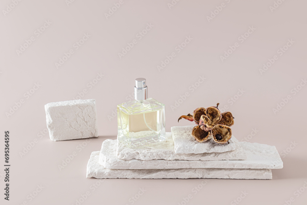 A chic bottle of perfume or eau de toilette on a podium made of white brick slices with a dried flower. A copy of the space. Pastel background. A chic bottle of perfume or eau de toilette on a podium made of white brick slices with a dried flower. A copy of the space. Pastel background.