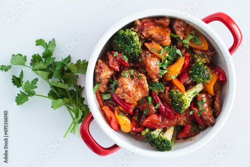 Stewed chicken fillet with vegetables in pan, white background. photo
