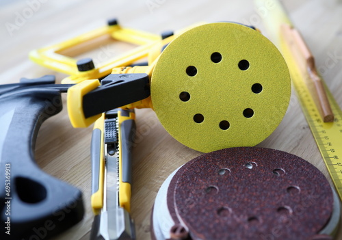 Close-up of bright yellow sander and box cutter on table. Professional electrical equipment for worker. Interior design. Renovation and construction site concept photo