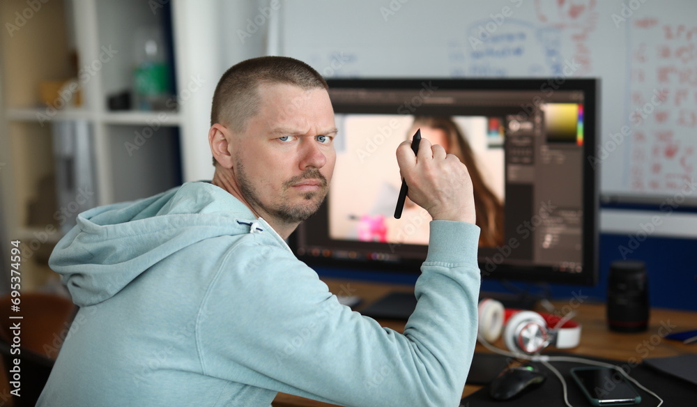Fototapeta premium Portrait of professional creative graphic designer creating masterpiece using computer. Concentrated middle-aged man in blue hoodie. Hobby and spare time concept