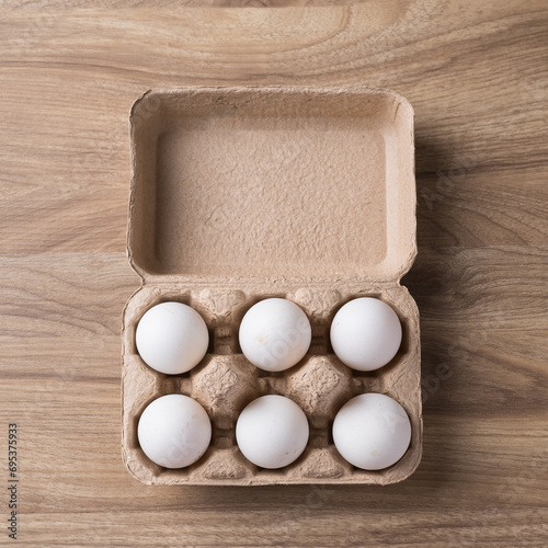Organic white leghorn egg from free range farm in paper tray on wooden table, Top view