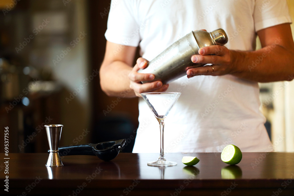 Barman at work, preparing cocktails. Pouring martini to cocktail glass