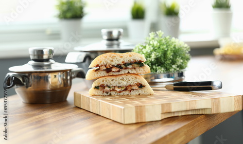 Close-up of delicious sandwiches with mixed stuffing. Fast food and calories. Unhealthy eating. Sharp knife on wooden desk. Brunch with fresh bread. Quick lunch and break from work concept