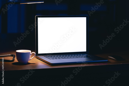Blank screen workspace with computer laptop on table at night, copy space.