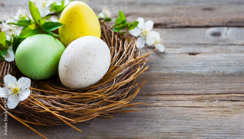 Easter eggs in a nest with spring flowers on a wooden background  copy space