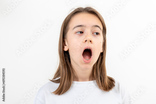 A girl on a white background yawns from boredom, a tired student.
