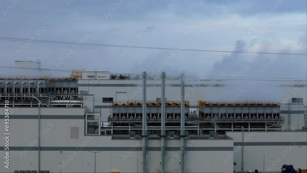 Smoking stacks of a factory lit by yellow lights, an aerial shot highlighting the environmental footprint of industry. Smoking stacks of a factory lit by yellow lights, an aerial shot highlighting the environmental footprint of industry.