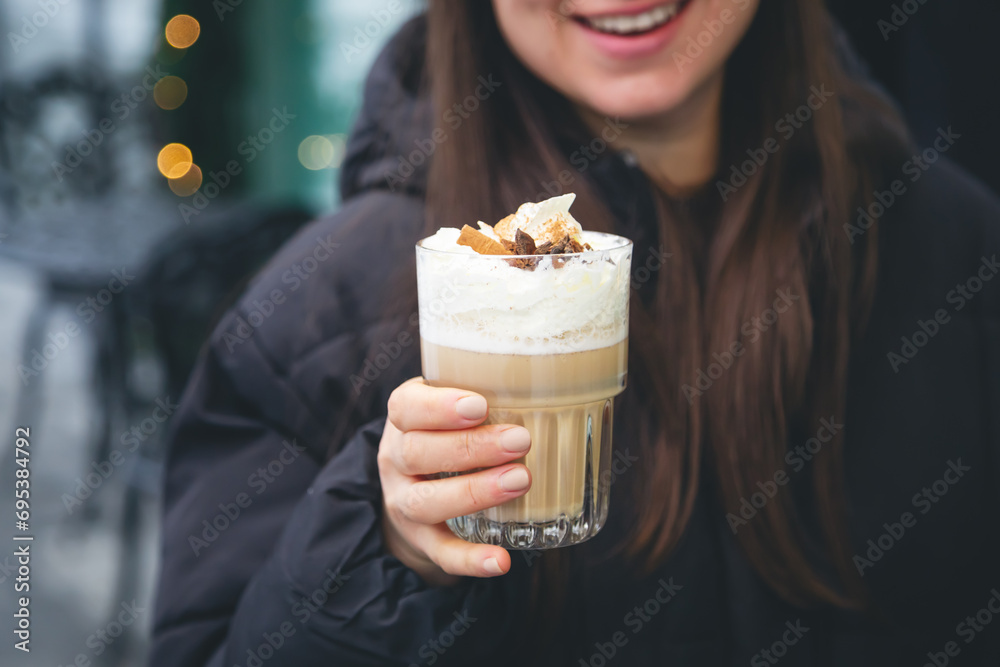 Coffee with cream, cinnamon and star anise in female hands outside. Coffee with cream, cinnamon and star anise in female hands outside.
