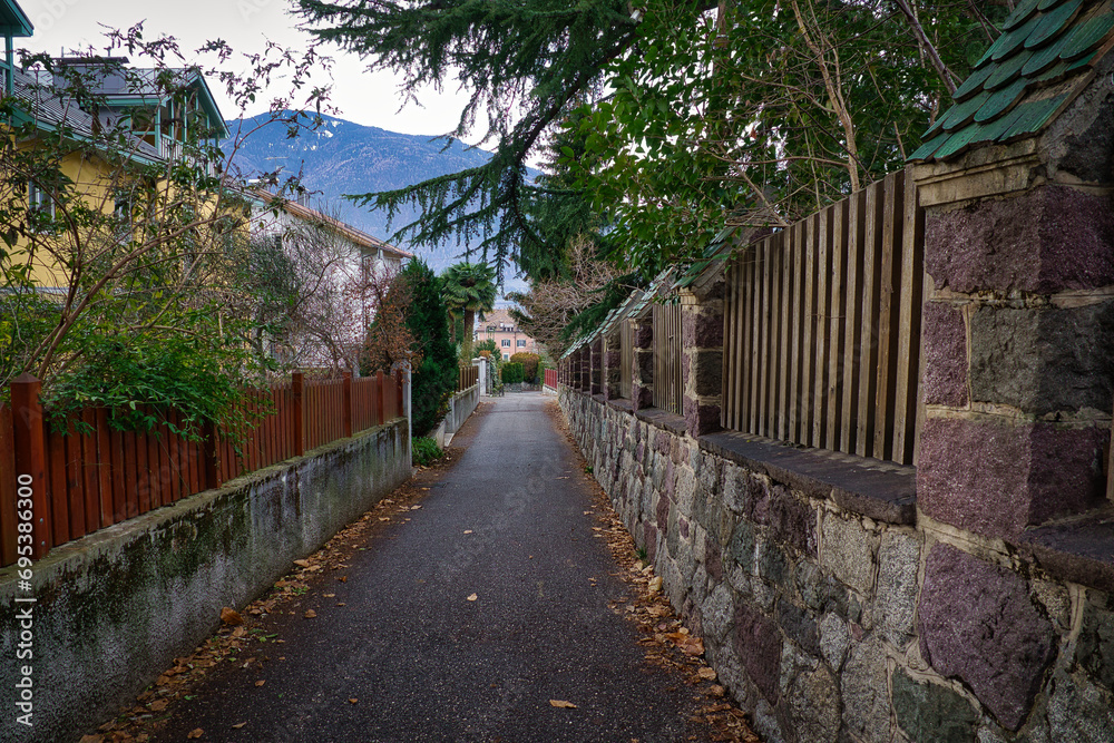 Eine schmale Gasse zwischen zwei Mauern mit einem Berg im Hintergrund