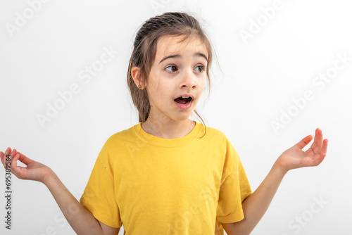 Little girl looks to the side in surprise on a white background isolated.