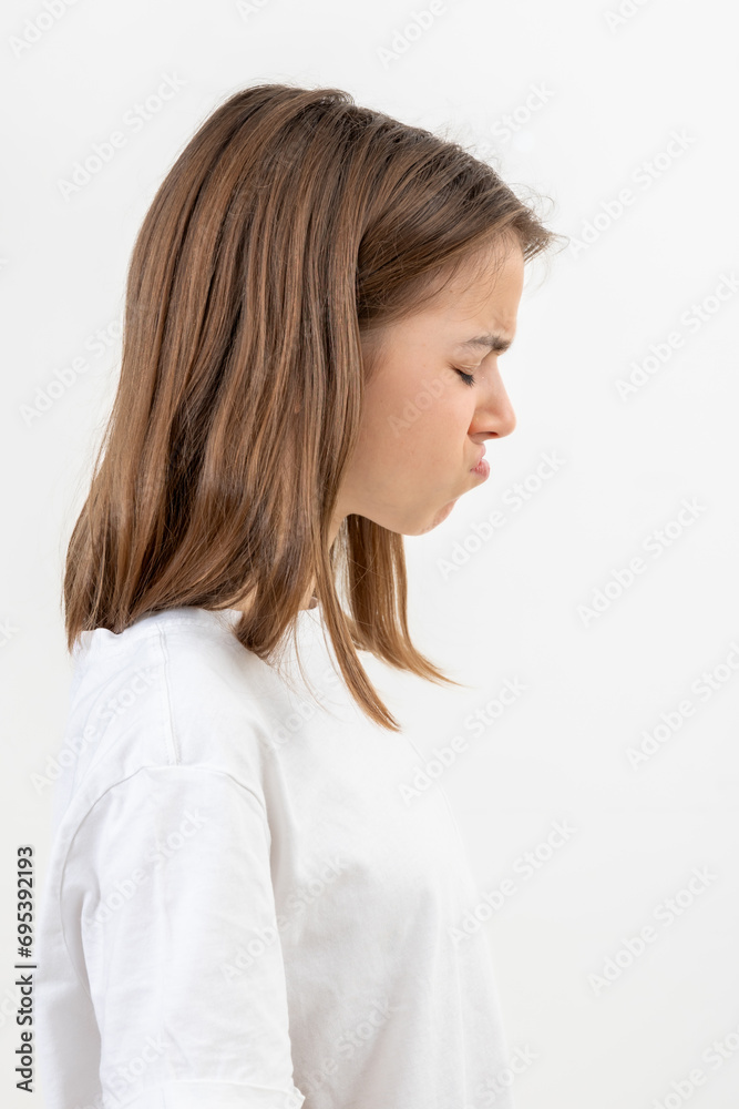 A teenager girl grimaces with displeasure on a white background, isolated. A teenager girl grimaces with displeasure on a white background, isolated.