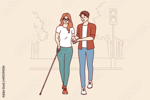 Man helps blind woman walk through park, enjoying city accessible environment for people with disabilities. Blind girl in sunglasses uses special cane to search for obstacles on way