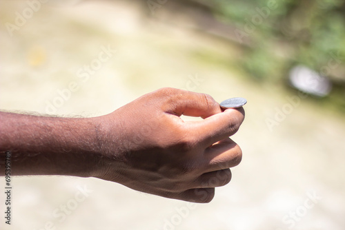 Money coins on the fingers of a man's hand and blurred background © Rokonuzzamnan