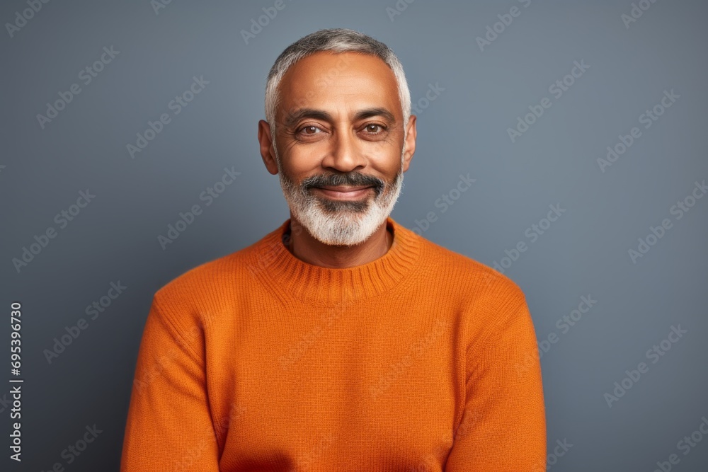 Portrait of a content indian man in his 50s wearing a cozy sweater against a soft orange background. AI Generation Portrait of a content indian man in his 50s wearing a cozy sweater against a soft orange background. AI Generation