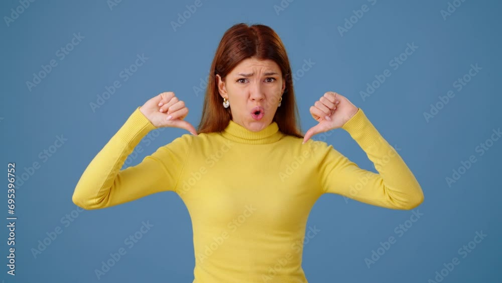 Displeased woman shows dislikes with thumb-down and waves hands Displeased woman shows dislikes with thumb-down and waves hands