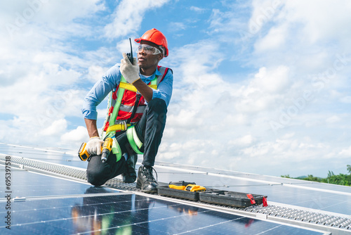African American engineer maintaining solar cell panels on factory building rooftop. Technician working outdoor on ecological solar farm construction. Renewable clean energy technology concept