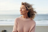 Portrait of a tender woman in her 50s wearing a cozy sweater against a serene seaside background. AI Generation