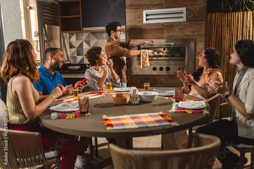 Jovem preparando uma refeição para seus convidados. Amigos comemorando a mesa.