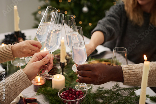 Closeup of hands of group of friends holding glasses with drinks during christmas home party