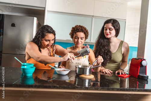 Amigas na cozinha fazendo brigadeiro, uma sobremesa tradicional brasileira.