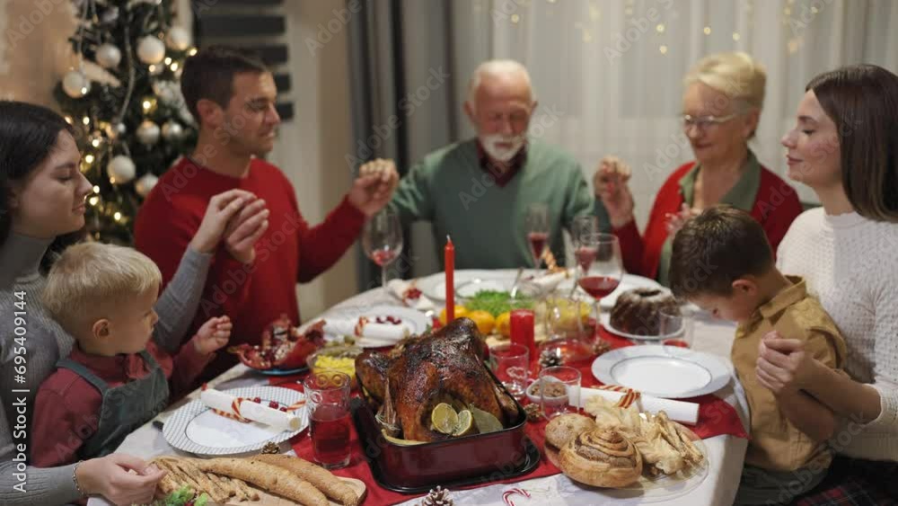 Family praying before eating tasty homemade food. Christmas dinner. Christmas decorations