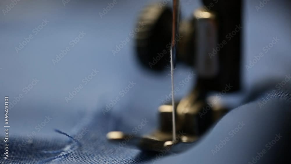 Close-up of blue fabric sewn on a sewing machine with white thread