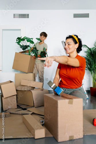 Smiling mother and son packaging and carrying boxes in new apartment