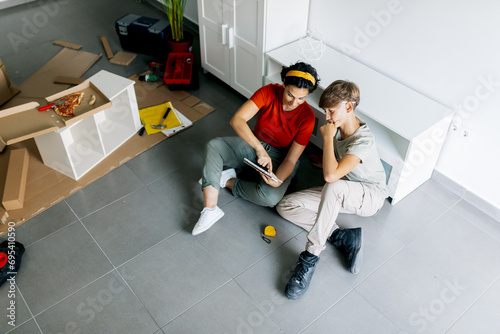 Single mother sitting together with son and pointing at notepad photo