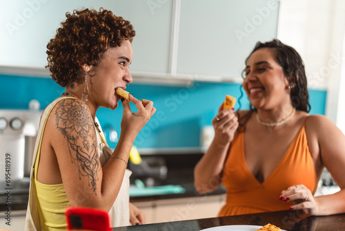 Young women in the kitchen eating tapioca dice, a traditional snack from Brazil. photo