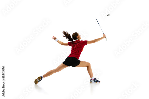 Badminton female athlete in motion, displaying attack and defense skills with finesse against white studio background. Concept of sport, active lifestyle, strength and power, action. Copy space.
