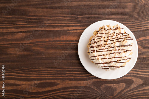 Tartlets with meringue cream and cup of coffee on brown wooden, top view, copy space.
